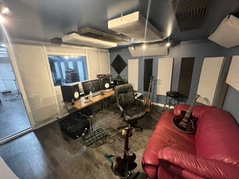 Billiam Records control room with guitars, desk, monitors, and acoustic treatment